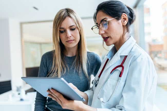 Ärztin mit Stethoskop bespricht und zeigt einer Patientin in der Praxis, die Ergebnisse