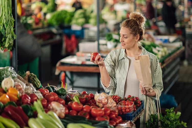 Nachhaltig leben: Eine Person kauft unverpacktes Obst an einem Marktstand.