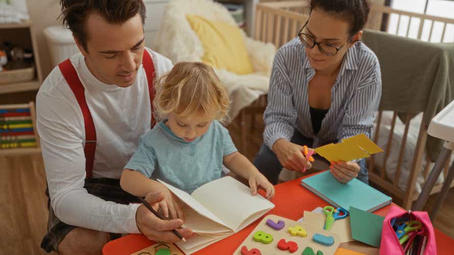 Eltern basteln mit ihrem kleinen Kind an einem Tisch. Der Vater hilft beim Malen, die Mutter schneidet Papier aus.