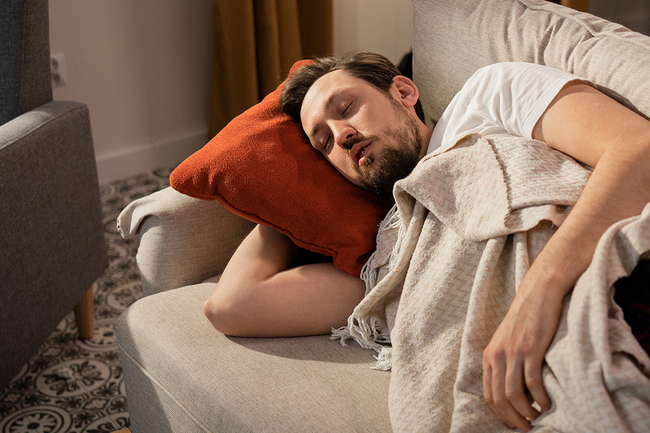 Ein Mann der auf einer Couch schläft.