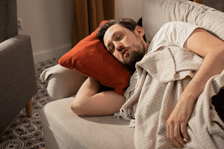 Ein Mann der auf einer Couch schläft.