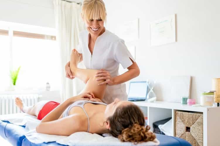 Osteopathin behandelt Patientin in einem Zimmer auf einer blauen Liege