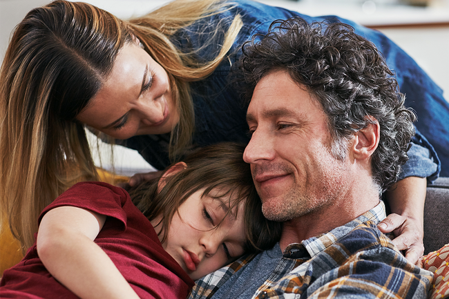 Eltern umarmen ihre Tochter.