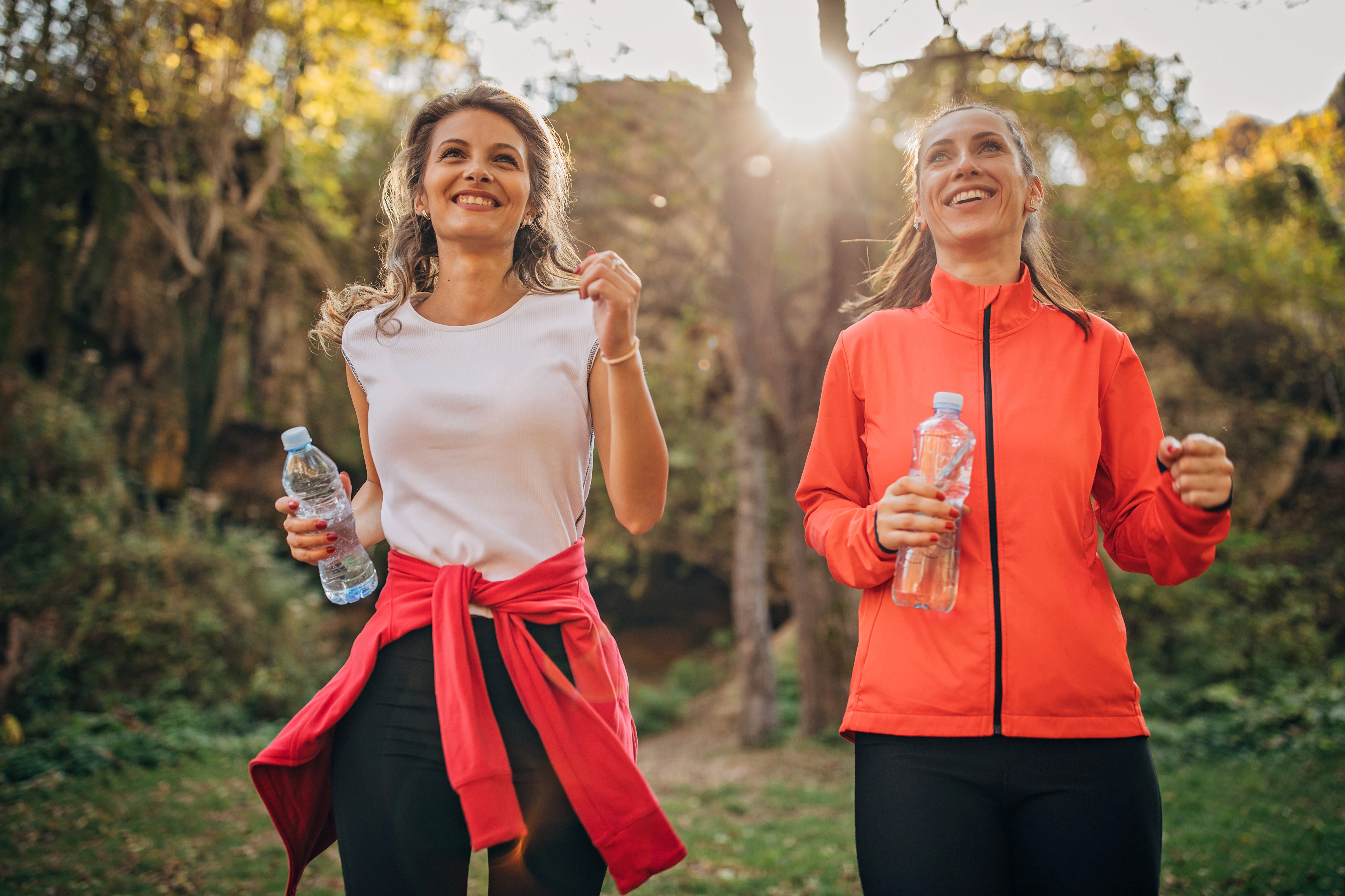 Two women, beautiful young ladies jogging together in nature.