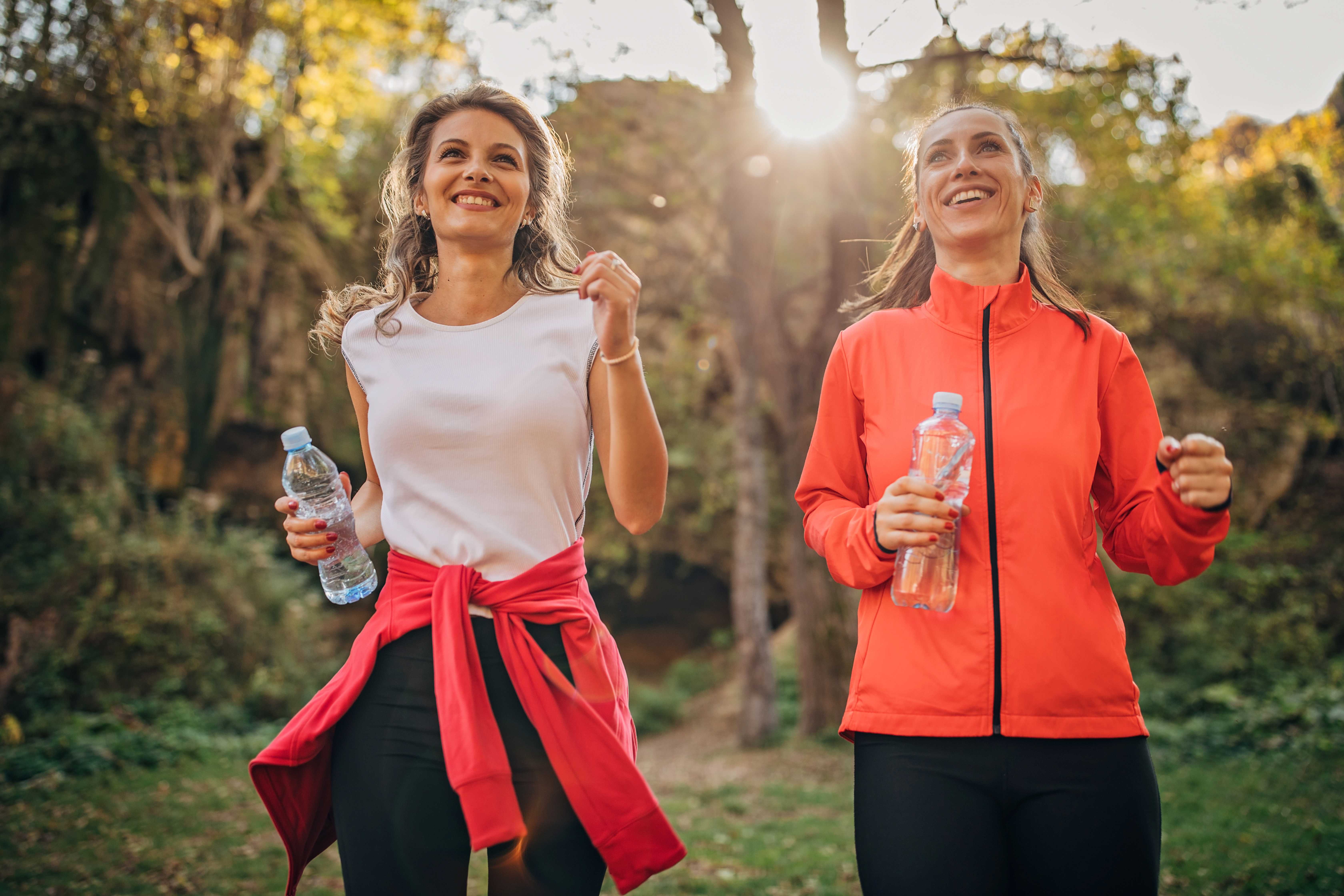 Two women, beautiful young ladies jogging together in nature.