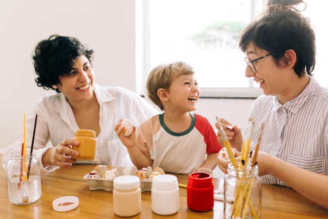 Eine Patchworkfamilie mit zwei Elternteilen und einem Kind sitzt an einem Tisch.