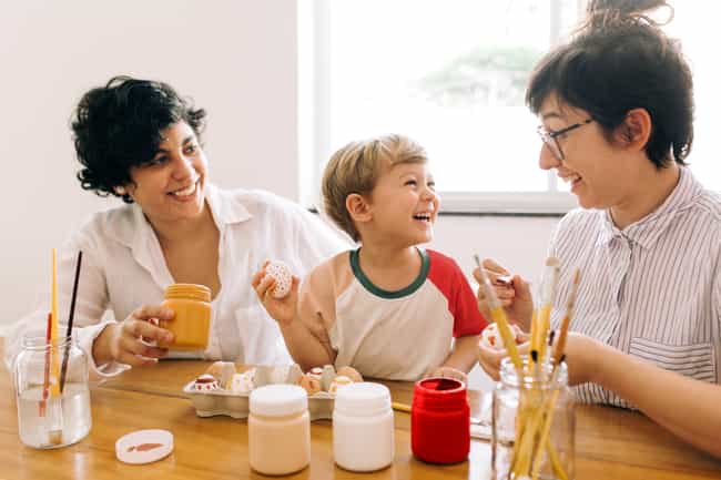 Eine Patchworkfamilie mit zwei Elternteilen und einem Kind sitzt an einem Tisch.